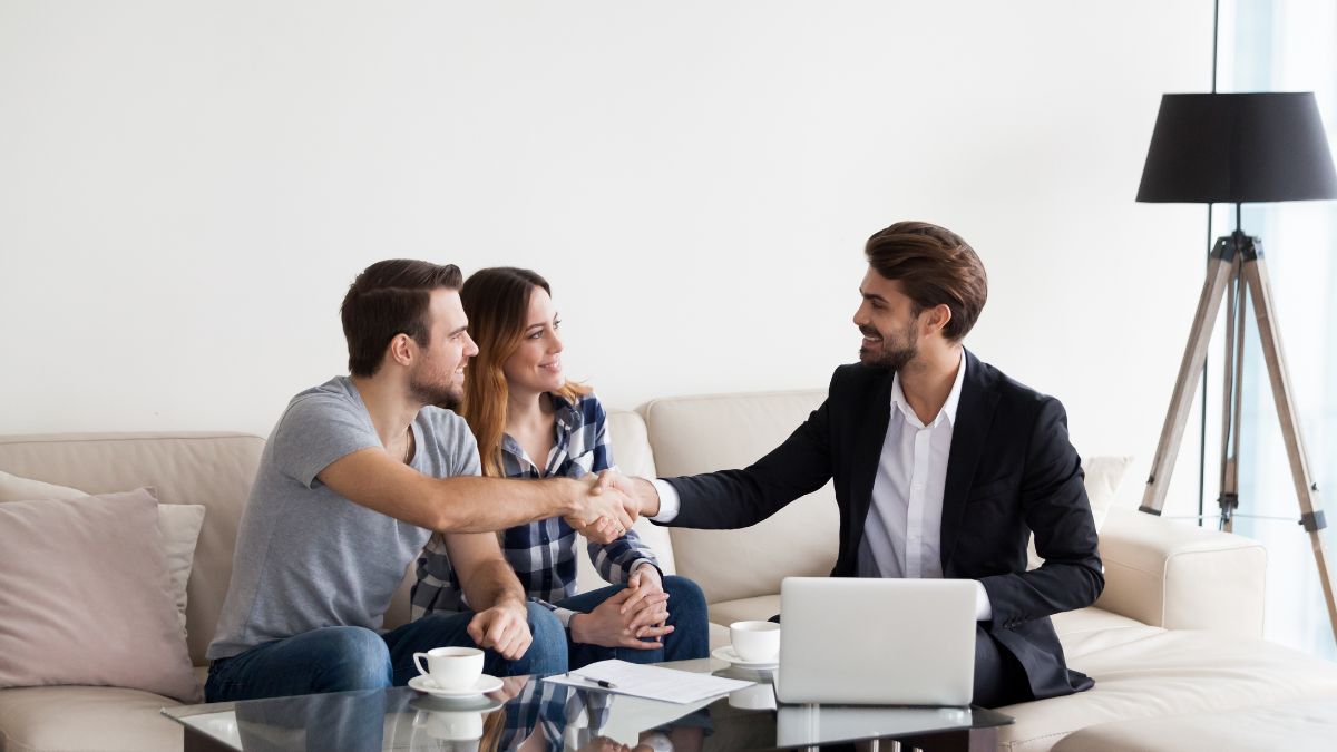 Website%20Dev.%20-%202024-11-04T112251.368 a couple shaking hands with a man in a suit while sitting on a white couch